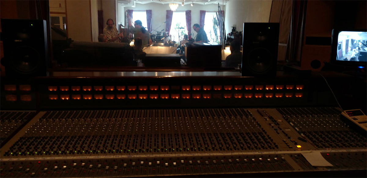 Photo of Gotham WInd Symphony in studio, scene through the recording booth window over the sound board